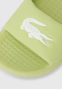 Ανοιχτό πράσινο σανδάλι με φάσα από ανθεκτικό καουτσούκ, με υφασμένο πέλμα και λευκό λογότυπο κροκοδείλου στη φάσα.