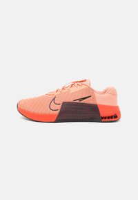 Baskets de sport légères de couleur orange avec une tige en maille, des accents noirs, une semelle rembourrée et un design texturé à l'arrière pour plus de stabilité.