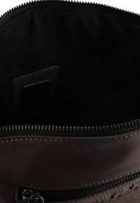 Donkere bruine leren tas met een gladde textuur, voorzien van een ritssluiting en een kleinere externe zak met zilverkleurige hardware.