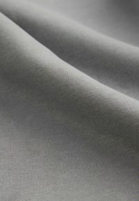 Grau fabric mit einer glatten, leicht strukturierten Oberfläche, die ein feines Webmuster zeigt. Das Material wirkt langlebig und vielseitig.