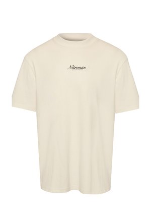 Camiseta beige de manga corta con cuello redondo y pequeño texto negro "Nitronix Rix Performance" centrado en el pecho.