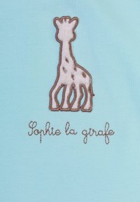 Tessuto blu con un disegno ricamato di una giraffa marrone e crema con dettagli sul corpo, accanto al testo "Sophie la girafe."