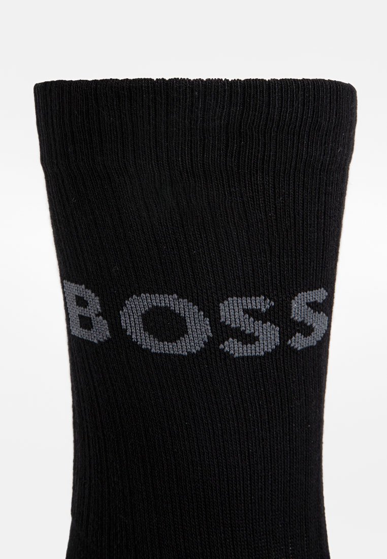 Zwarte geribde sokken met het woord "BOSS" in het grijs, prominent afgebeeld langs de enkelrand. Eenvoudig ontwerp met een zachte textuur.