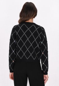 Maglione nero a maglia con motivo a diamante grigio, che presenta accenticolorati simili a gemme sulle maniche e orlo a coste. Design cropped.