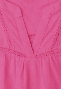 Tissu rose avec encolure en V et détails de dentelle, présentant une texture douce et une couture froncée sous la zone de la poitrine.