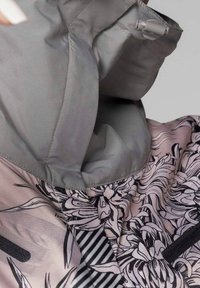 Giacca con motivo floreale nei toni del rosa e grigio, realizzata in un tessuto leggero, con dettagli a righe nere e colletto regolabile.