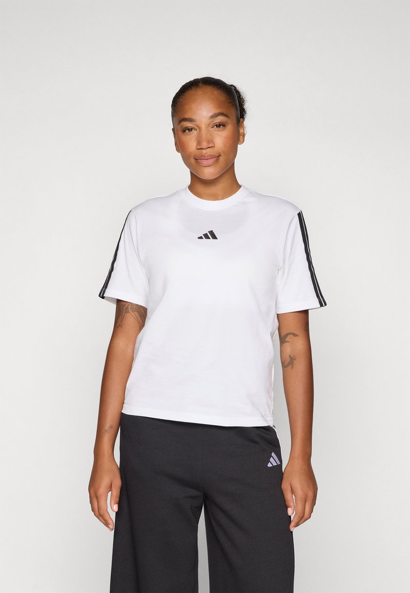 Bela kratka majica s kratkimi rokavi iz zračnega materiala, ki na prsih vsebuje črni Adidas logo in črne črte na rokavih.