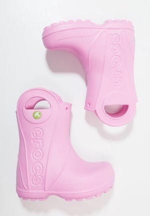 Paire de bottes de pluie Crocs roses avec semelles texturées et poignées circulaires, posées sur un fond blanc.