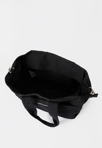 Μαύρη τσάντα tote Björn Borg με χερούλια, ανοιχτή κορυφή που δείχνει εσωτερικό χωρίς περιεχόμενο, μεταλλικοί δακτύλιοι στα πλάγια για προαιρετική θήκη ώμου.