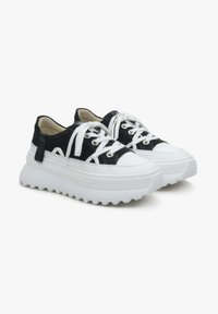 Zwart-witte chunky sneakers met een gestructureerde bovenzijde, ronde witte neus, dikke witte zool en witte veters. Bevat een label aan de zijkant.