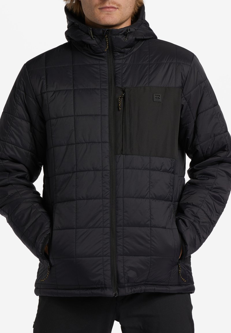 Schwarze gesteppte Jacke mit Kapuze, ausgestattet mit einer kontrastierenden schwarzen Brusttasche, Reißverschluss und strukturiertem Stoff. Akzente umfassen einen Kordelzug und Besatz.