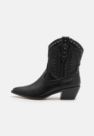Bottes de cowboy en cuir noir avec des orteils pointus, des coutures décoratives et des clous en métal le long du haut. Talon empilé et finition texturée.