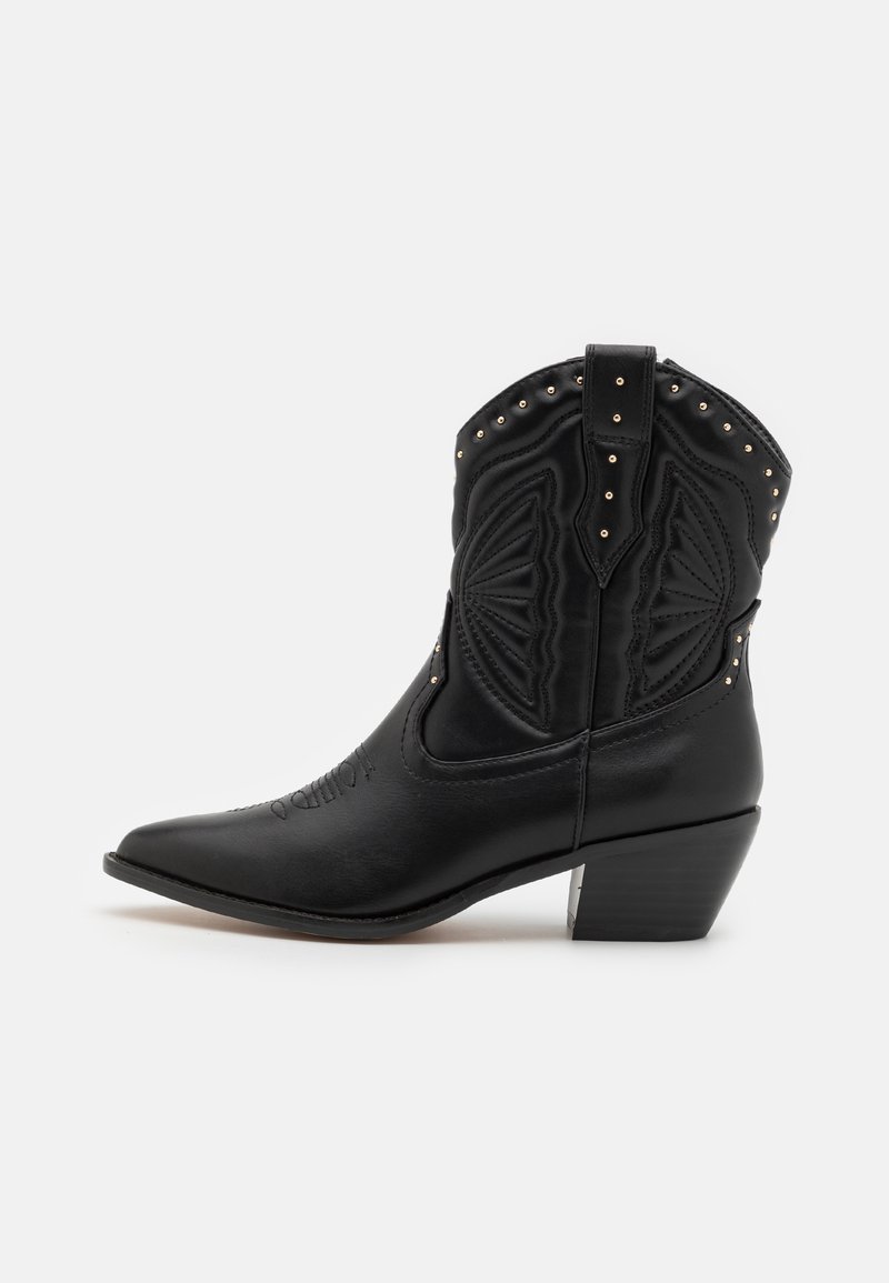 Botas de cowboy em couro preto com bicos pontudos, costura decorativa e rebites metálicos ao longo da parte superior. Salto empilhado e acabamento texturizado.