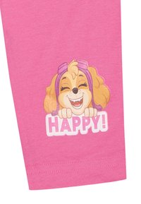 Prenda de algodón rosa con un gráfico de un perro de dibujos animados sonriendo y la palabra "¡FELIZ!" en texto blanco debajo. Colores brillantes y textura suave.