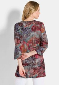 Kleurige tuniek met een bloemen- en abstract patroon, voorzien van driekwart mouwen en een losse pasvorm. Gemaakt van een lichte stof.