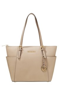 Borsa tote beige Michael Kors con due manici, caratterizzata da un logo dorato e da un charm decorativo, progettata per un uso quotidiano elegante.