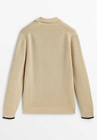 Beżowy sweter dziany o prążkowanej fakturze, z wysokim kołnierzem i czarnymi prążkowanymi mankietami. Tył jest gładki, bez dodatkowych detali.