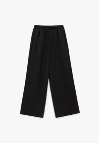 Zwarte, wijde broek met een gestructureerde stof en een elastische tailleband. Het ontwerp heeft een losse, ontspannen pasvorm zonder zichtbare sluitingen.