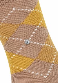 Beige- und gelb gestrickte Socke mit Rautenmuster, akzentuiert durch weiße Kreuzstichnaht. Verfügt über einen Burlixton-Logo-Button.