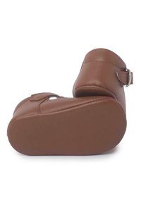 Zapatos de cuero marrón con punta redondeada, suela plana y detalle de hebilla lateral. Textura suave y diseño limpio, adecuados para diversas ocasiones.
