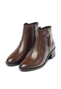 Stivali ankle in pelle marrone con punta affusolata, cerniera laterale e dettagli in metallo dorato. Tessuto liscio e tacco basso a blocco.