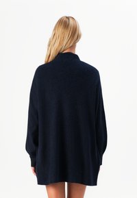 Pull en maille surdimensionné bleu marine avec une finition texturée, présentant un col et des manches longues, affiché de dos.