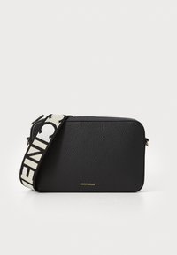 Borsa a tracolla in pelle nera con finitura testurizzata, dotata di una spallina a strisce audaci e dettagli in oro del logo. Forma rettangolare e design minimalista.