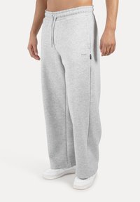 Gray sweatpants with an elastic waistband, drawstring, and tapered legs, made of soft fabric. Features side pockets and a small logo tag.