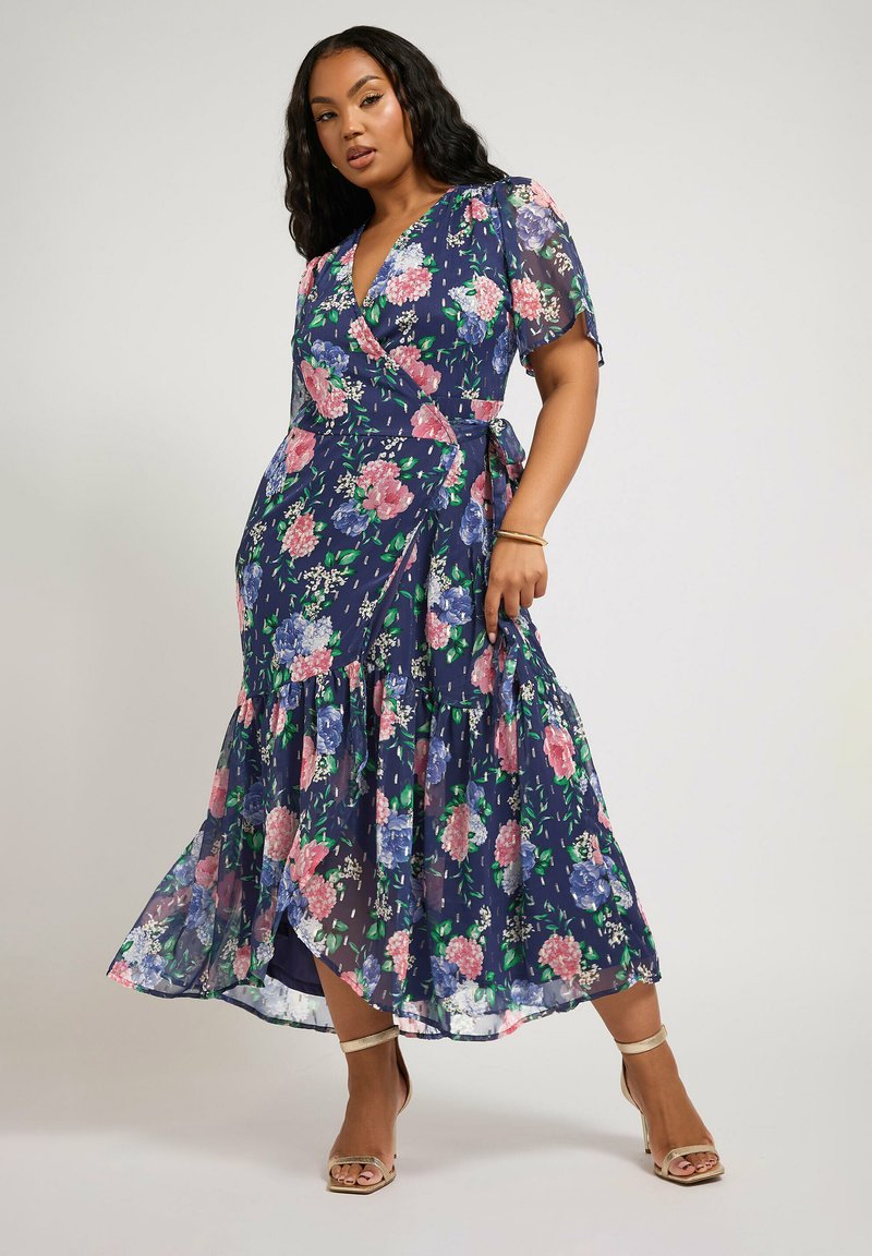 Abito max lungo floreale navy con design avvolgente, maniche a sbuffo e orlo a più strati. Presenta fiori rosa e blu su un tessuto trasparente.