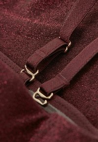 Bordowy materiał o teksturowanym, błyszczącym wykończeniu, z regulowanymi ramiączkami i złotymi akcentami.