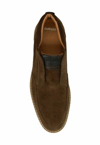 Chaussure slip-on en daim marron avec des panneaux élastiques sur les côtés, doublure en cuir beige et coutures blanches sur la semelle. Présente un accent de marque noir.