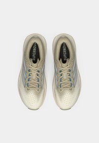 Μπεζ αθλητικά παπούτσια με γκρι ρίγες, υφή στην επάνω επιφάνεια, στρογγυλεμένη μύτη και μπλε λεπτομέρειες. Δαντέλες κι εμφανές λογότυπο στην εσωτερική σόλα.