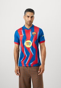 FC Barcelona marškiniai mėlynos ir raudonos spalvos su zigzago raštu, turi apykaklę, Nike logotipą, klubo emblemą ir Spotify logotipą priekyje.