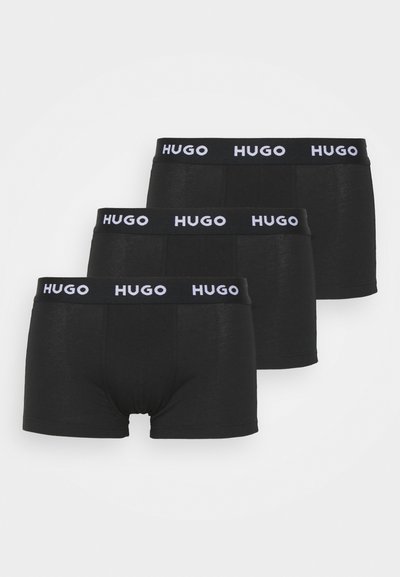 Boxer-briefs noirs avec une large ceinture élastique arborant la marque "HUGO" en blanc. Le matériau semble lisse avec une coupe ajustée. Trois pièces incluses.