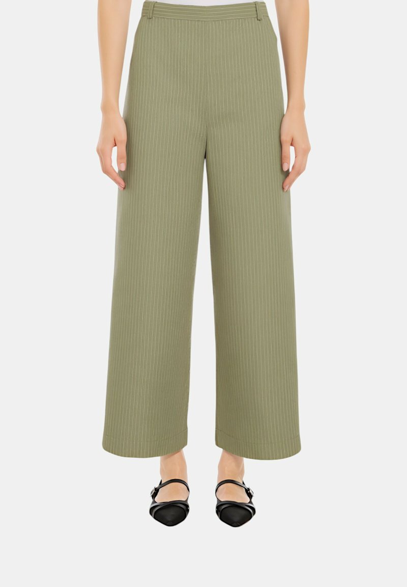 Pantaloni a gamba larga verde oliva con righe verticali, caratterizzati da una vita alta e una trama liscia. Indossati con scarpe flat nere.
