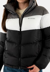 Giacca a vento imbottita con un design a blocchi di colore nero, bianco e grigio. Presenta una zip completa e un colletto alto. Realizzata in un materiale lucido e isolante.