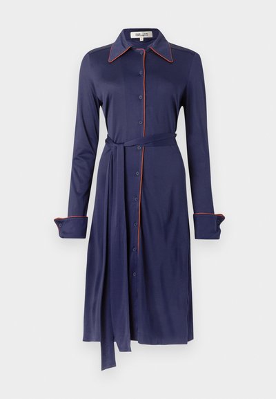 Vestido azul-marinho com gola, abertura frontal com botões, mangas compridas e acabamento em piping laranja contrastante. Apresenta cintura com cinto e tecido macio.