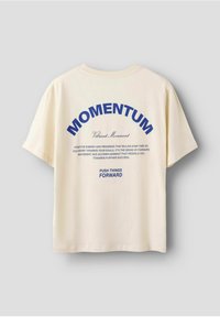 Cremefarvet bomulds t-shirt med blå grafisk tekst: "MOMENTUM," "Vibrant Movement," og "PUSH THINGS FORWARD." Korte ærmer, løs pasform.