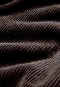 Close-up of dark brown corduroy fabric showing soft, raised parallel ridges and valleys with visible texture details.