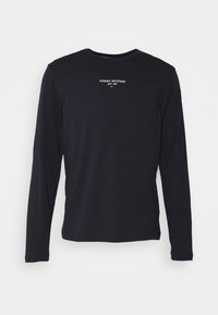 Černé tričko s dlouhým rukávem vyrobené z bavlny, s malým bílým logem "TOMMY HILFIGER EST. 1985" umístěným na středu hrudníku.