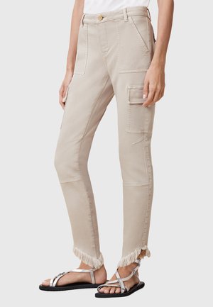Beige cargobroek met een slim fit, voor- en zijzakken en rafelige zomen. De stof is lichtgewicht met een soepele textuur.
