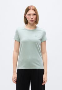 Μπλουζάκι κοντομάνικο σε μέντα από απαλό βαμβάκι με στρογγυλή λαιμόκοψη και μικρό κεντημένο λογότυπο στο στήθος. Απλός σχεδιασμός, εφαρμοστή γραμμή.