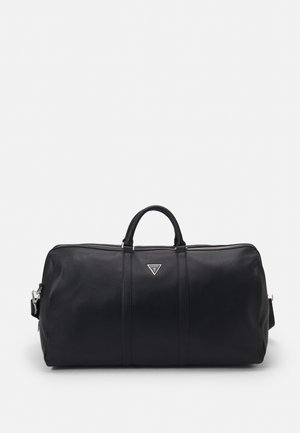 Sac polochon en cuir noir avec poignées supérieures, fermeture éclair et logo Guess triangulaire au centre avant.