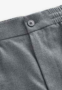 Graue Stoffhose mit glatter Textur, ausgestattet mit einem vorderen Knopfverschluss und leichter Raffung am Bund.