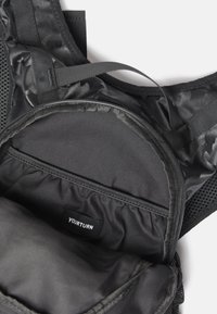 Zaino nero con dettagli in rete, interno in tessuto liscio, scomparto con zipper arrotondata e etichetta del marchio "YOURTURN" visibile all'interno.