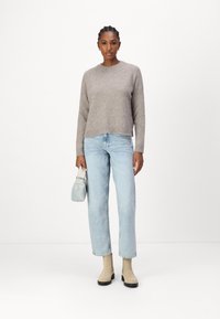 Lichtgrijze gebreide trui met een ronde hals, gecombineerd met lichtblauwe rechte jeans. Beige enkellaarsjes en een kleine blauwe handtas.