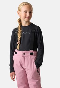 Różowe spodnie narciarskie z regulowanymi czarnymi szelkami, kieszeniami bocznymi na zamek oraz czarną bluzką z długim rękawem z motywem górskim. Gładka tekstura.