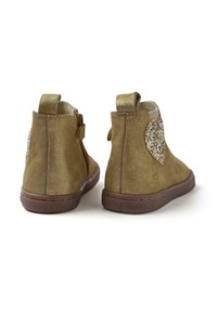 Botines de ante marrón con un acento de corazón brilliante en el tacón, cierre de cremallera y suela de goma marrón texturizada.