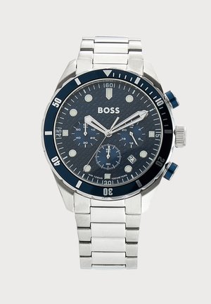 Ρολόι χρονογράφος Hugo Boss από ανοξείδωτο ατσάλι με μπλε υφασμάτινο καντράν, περιστρεφόμενη στεφάνη, ένδειξη ημερομηνίας και τρεις υποκλίμακες σε μεταλλικό μπρασελέ.