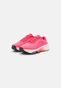 Nike löparskor i starkt rosa, med en ovandel av mesh, dämpad sula och en svart gummiyttersula med synliga luftkammare i hälen.